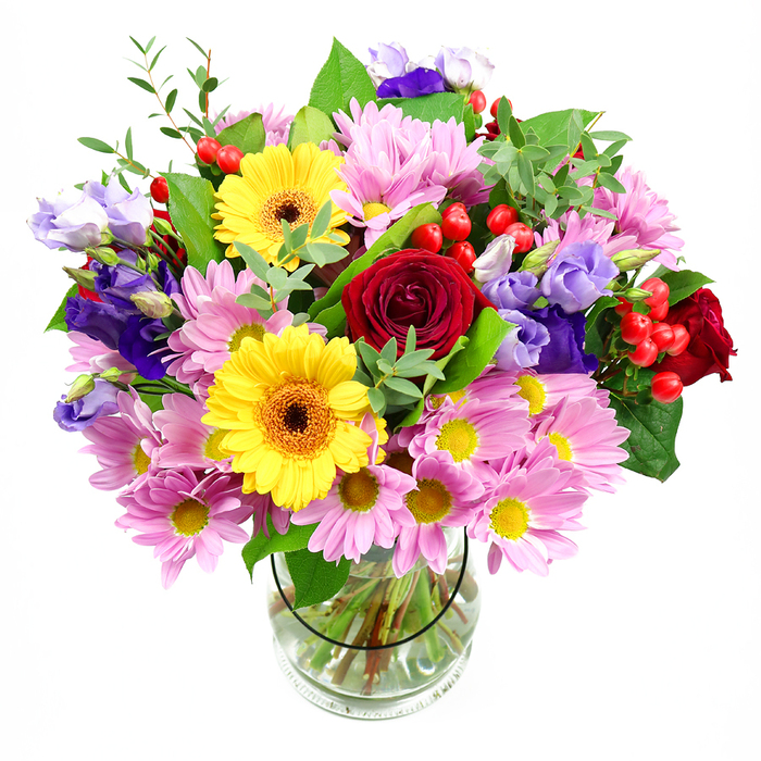 A generous, hand-crafted bouquet stands proudly in a transparent glass vase, the pure white background highlighting every colour and contour of the arrangement. At the core, rich red roses with tightly layered, velvety petals create depth and a sense of heartfelt emotion. Close by, two radiant yellow gerbera daisies spread their wide, smooth petals around deep, textured centres, giving the design an immediate sense of warmth and cheer. Encircling these central blooms, pink daisies and chrysanthemums spill outward, their soft, feather-like petals and small yellow centres combining to form a gentle, cloud-like halo. Threaded artfully through this pastel softness are refined lisianthus blossoms in shades of purple and lavender, their bell-shaped flowers and curled edges lending a cool, contemporary grace. Dotted throughout are glossy red hypericum berries, round and jewel-like, which punctuate the bouquet with touches of bright colour and playful dimension. A mix of greenery in varying shades of green-from dark, polished leaves to lighter, slightly wild sprigs-frames the flowers, adding structure and the feeling of something freshly gathered. The clear vase itself offers a view of the straight, neatly trimmed stems immersed in clean water, emphasising the professional conditioning behind the scenes. The overall mood is one of relaxed celebration, like a bouquet waiting on a Beaconsfield kitchen table after a visit to the Old Town or a stroll under the mature trees nearby. This design feels perfect for birthdays, thank you gifts, or to send a warm, colourful message to someone special in the Beaconsfield area.